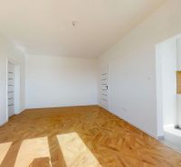 A white room with a wooden decor floor, entrance to the kitchen in a 3-room apartment.