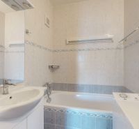 Bathroom with a bathtub, sink, and washing machine in a 3-room apartment.