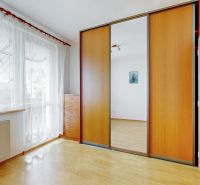 A bright interior of a 3-room apartment with a large mirrored wardrobe and a wooden decor floor.