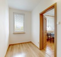 A hallway in a 3-room apartment with a wooden decor floor and a view into the neighboring room.