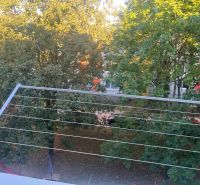 View from the balcony of a 2-room apartment in Rožňava to a green park with cars.