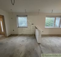 An unfloored interior of a family house with two windows and a door.