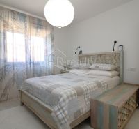 Bright bedroom with a double bed in a holiday apartment, light curtains, and a decorative floor.