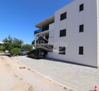 The exterior of a holiday apartment in Srima with two parked cars and a blue sky.