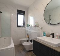 Bathroom in a holiday apartment with a bathtub and a sink, floor with wooden decor.