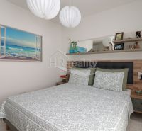 Bedroom in a holiday apartment with a painting by the sea and a shelf above the bed.