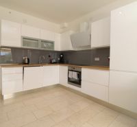 A kitchen in a holiday apartment with white cabinets and appliances, and a wooden decor floor.