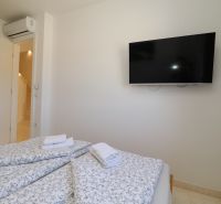 Recreational apartment with air conditioning, TV, and a bed with floral bedding.