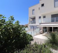 A holiday apartment in Tribunj with a terrace and a green garden under the blue sky.