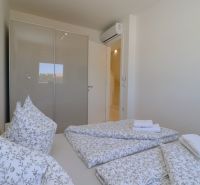 Bedroom in a holiday apartment with a bed, built-in wardrobe, and air conditioning.