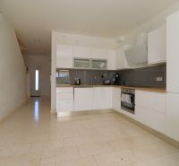 A kitchen in a holiday apartment with white cabinets and a light wooden-decor floor.