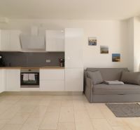 A kitchen with a sofa in a holiday apartment, wooden decor flooring, tasteful decorations.