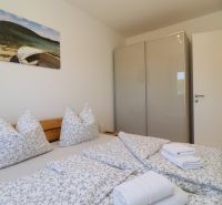 Bedroom in a holiday apartment with a double bed, wardrobe, and decorative painting.