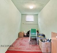 A narrow room in a family house with boxes and a green chair.