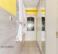 A hallway with a yellow wall, white furniture, and a window in a family house.