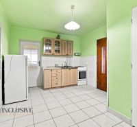 A kitchen in a family house with light green walls, tiles, and a wooden kitchen unit.
