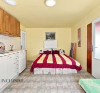 Simple bedroom setup with a kitchenette in a family house, white-brown furniture, bed.