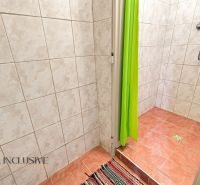 A bathroom in a family house with tiles and a shower in a shade of green.