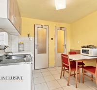 A kitchen in a family house with yellow walls, tiles, and a table with chairs.