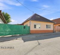 A family house in Veľký Meder with an orange facade and a green gate on the street.
