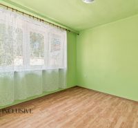 A room with a window, green walls, and a wooden-patterned floor in a family house.
