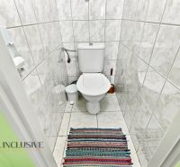 A bathroom with white tiles and a colorful rug in a family house.