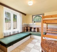 A room in a family house with a bunk bed and a couch, curtains letting in light.