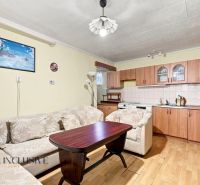 Living room with a kitchenette, sofa, and wooden decor flooring in a family house.