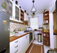 A kitchen in a 4-room apartment with white cabinets, a stove, a refrigerator, decorative tile.