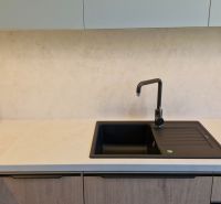 Kitchen unit in a 3-room apartment with cabinets and a black sink.
