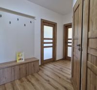 Interior of a 3-room apartment with a wood-patterned floor, wooden doors, and a coat rack.