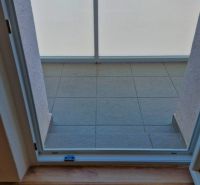 View from a 3-room apartment to a balcony with glass and a wooden decor floor.