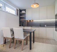 Kitchen in a 4-room apartment, wooden decor flooring, light cabinets, and a dining table.
