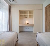 A room in a 4-room apartment with shelves, a table, and beds, flooring with a wood decor.