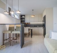 A kitchen in a 4-room apartment with bar stools, a stove, and a floor with a wood decor.