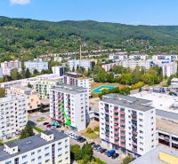 A view of the commercial premises at Dvory in Púchov with nearby greenery and rooftop parking.