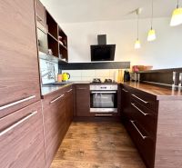 Kitchen in a studio apartment with wood-patterned flooring, dark cabinets, induction cooktop.