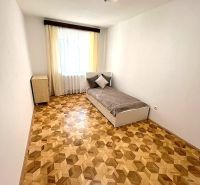 A room with a bed, a wooden decor floor, minimalist furniture in a 3-room apartment.