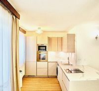 A kitchen in a 3-room apartment with white cabinets and a wooden decor floor.
