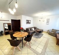 Living room in a three-room apartment with tiles, a sofa, and a dining table.