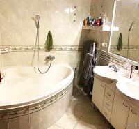 A bathroom with a corner bathtub and double sink in a three-room apartment.