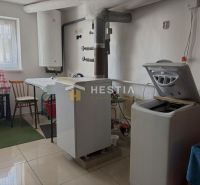 Laundry room in a family house with a washing machine, table, and water heating boiler.