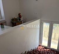 Interior of a family house with a colorful carpet, staircase, and decorative items.