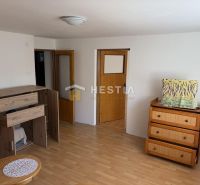 A room in a family house with furniture, a wooden decor floor, and white walls.
