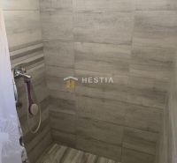 Shower corner in a family house with wood-patterned tiles and a curtain.