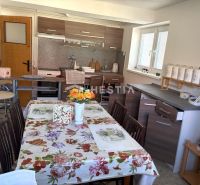A kitchen in a family house with a floral tablecloth and a kitchen unit with a wooden decor.