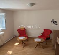 Interior of a family house with two chairs, tables, and a wooden-patterned floor.