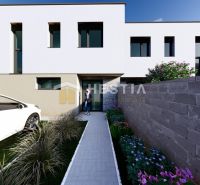 A modern house facade with a car and a landscaped garden in Rovensko.