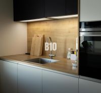 A kitchen with wooden decor, a sink, black cabinets, appliances, and wooden countertops in a 3-room apartment.
