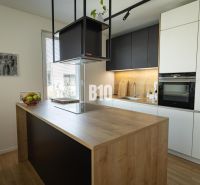 A kitchen in a 3-room apartment with an island and a wooden decor floor.